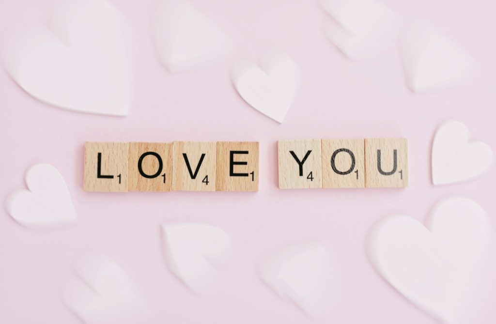 "Love you" in Scrabble letters against a background of hearts