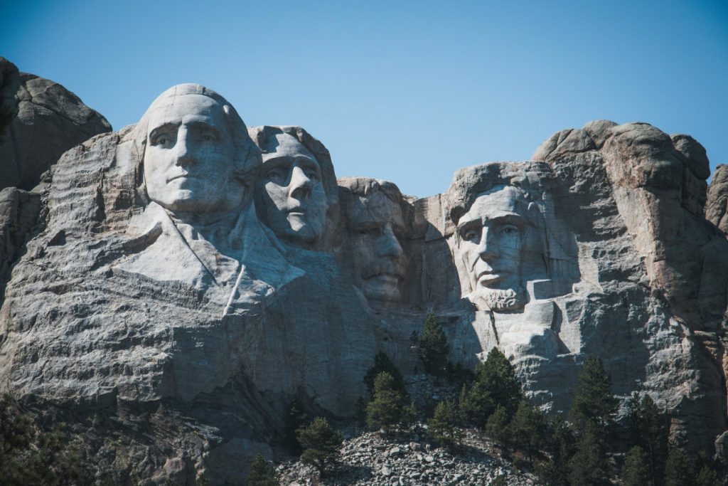 Mt. Rushmore with Washington, Jefferson, and Lincoln highlighted and Roosevelt in shadow.